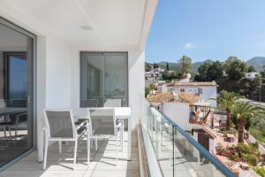 a balcony with a white table and chairs and a view at Central Apartment with a view in Mijas