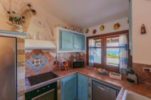 a kitchen with blue cabinets and a window at La Terrazza sul mare in Palau +25 photos