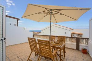 a patio with a table and chairs and an umbrella at Calida Vivienda Accesible in Caleta De Fuste