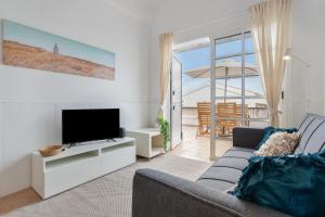 a living room with a couch and a flat screen tv at Calida Vivienda Accesible in Caleta De Fuste