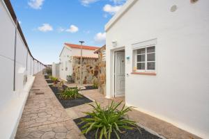 a white house with a pathway between two buildings at Calida Vivienda Accesible in Caleta De Fuste