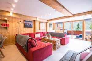 a living room with a red couch and a table at Chalet Vithos en Demi-pension in Les Bruyères