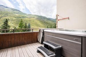 a bath tub on a deck with a view of a mountain at Chalet Vithos en Demi-pension in Les Bruyères