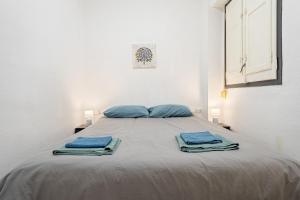 a bed with blue pillows and towels on it at Sonrisita in Miami Platja