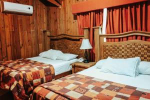 two beds in a room with wooden walls and wood at Cumbres Hotel y Cabañas in Gómez Farías