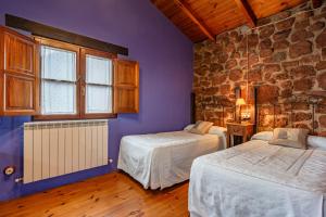 a bedroom with two beds and a stone wall at La Pumarada in Villaviciosa