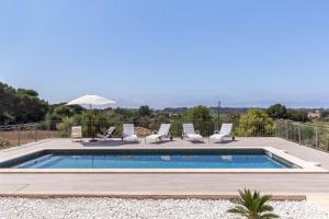 a swimming pool with chairs and an umbrella at Colonies in Ses Salines