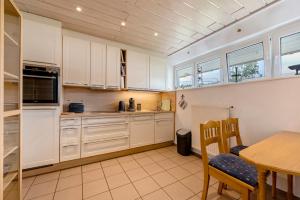 a kitchen with white cabinets and a table and chairs at Heimatglück Vulkaneifel mit Sauna in Salm