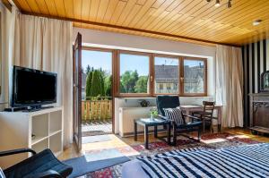 a living room with a television and a table and chairs at Vronis Ferienwohnungen in Mühlingen