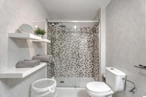 a white bathroom with a shower and a toilet at Apartamento Retama in Adeje +13 photos