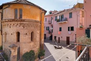 an old building in an alley with pink buildings at Casa Acqua Mare Parasio in Imperia