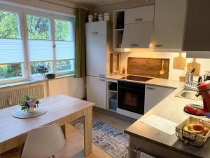 a kitchen with white appliances and a table with a bowl of fruit at Ferienwohnung Bullentäle in Albstadt