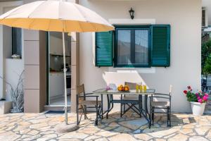 a table and chairs with an umbrella on a patio at Nikoleta Apartment A in Nikiana