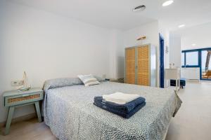 a white bedroom with a bed and a table at Calafellmar loft in Calafell