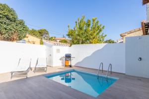 a swimming pool with two chairs next to a white wall at El Pinito Moraira in Moraira