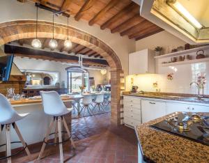 a kitchen with an archway and white cabinets and bar stools at Podere Erbolino in Gaiole in Chianti
