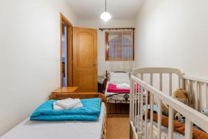 a bedroom with a crib and a room with two beds at Moraki Apartment 1 Andros in Korthi