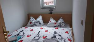 a bed with four pillows and a comforter with hearts at Ferienwohnung in Spreewaldnähe in Kolkwitz