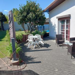 a patio with two white chairs and a table at Ferienwohnung in Spreewaldnähe in Kolkwitz