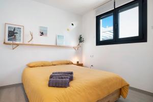 a bedroom with a bed with a yellow blanket and a window at Casa Maracuya in Tarifa
