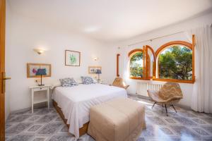 a bedroom with a bed and two chairs and a window at Ca Ses Mestres in Santanyi