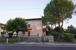 a white house with a fence next to a street at Oliva's House con giardino in Palazzolo dello Stella