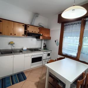 a kitchen with white cabinets and a white table at Oliva's House con giardino in Palazzolo dello Stella