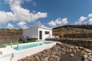 a house with a swimming pool and a stone wall at Casa Jonas in Tías