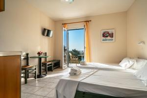 a hotel room with two beds and a balcony at Anemona studio C in Kefallonia
