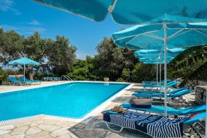 a swimming pool with blue umbrellas and chairs next to a pool at Anemona studio C in Kefallonia