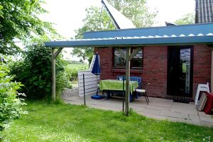 a patio with a table and a blue roof at Ferienwohnung Achterndiek in Galmsbüll