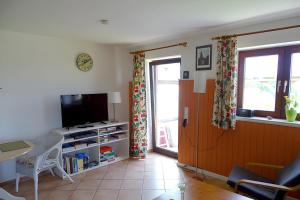 a living room with a television and a table and chairs at Ferienwohnung Achterndiek in Galmsbüll