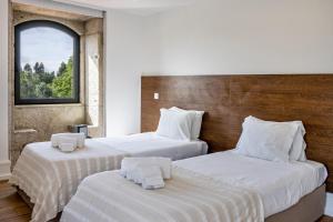 two beds in a hotel room with a window at Casa do Mestre T2 in Vila de Punhe +19 photos