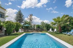 a swimming pool in a yard with chairs and trees at Casa Cantarrana in Arriate
