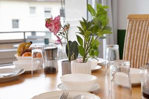 a table with white dishes and plants on it at Business Apartment in Oberkochen in Oberkochen