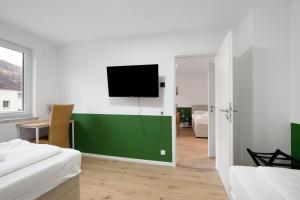 a bedroom with a flat screen tv on a green wall at Business Apartment in Oberkochen in Oberkochen