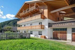 a house with a wooden balcony and a fence at Oberhemberger Hof Feldthurns in Feldthurns