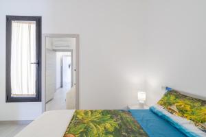 a white bedroom with a bed and a mirror at Villetta Vanessa in Avola