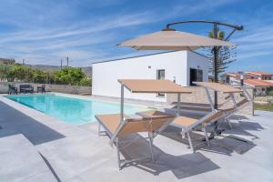 a pool with a table and chairs and an umbrella at Villetta Vanessa in Avola