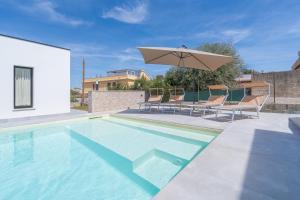 a swimming pool with two chairs and an umbrella at Villetta Vanessa in Avola
