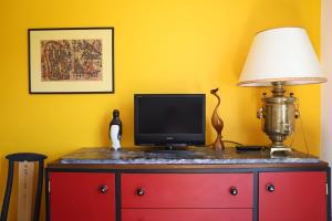 a television on a red dresser with a lamp at Txori Etxea in Arcangues