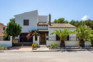 a white house with a gate and palm trees at Pomeres Nou in Sa Coma