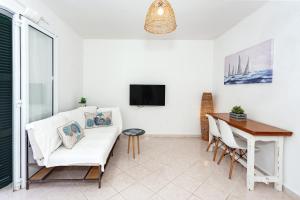 a living room with a white couch and a table at Villa Goyo in Cala en Bosc