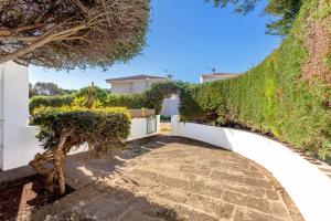 a walkway leading to a house with a hedge at Villa Goyo in Cala en Bosc