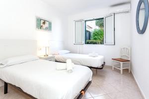 two beds in a room with a window at Villa Goyo in Cala en Bosc