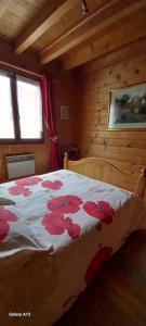 a bedroom with a bed with red flowers on it at Chalet Jura in Doucier