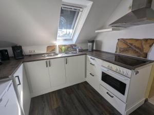 a kitchen with white cabinets and a sink and a stove at Ferienwohnung Alafia in Veitsbronn +10 photos