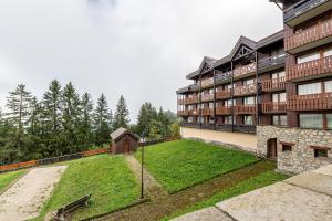 an apartment building with a grassy yard in front of it at Le cheval blanc E7 in Valmorel