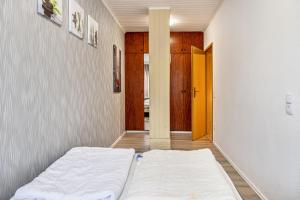 a white bed in a room with a door at Günthers Wattstube in Schweiburg