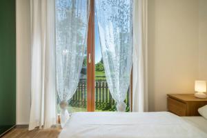 a bedroom with a bed and a window with curtains at Ferienhaus Im Tobel in Deggenhausertal